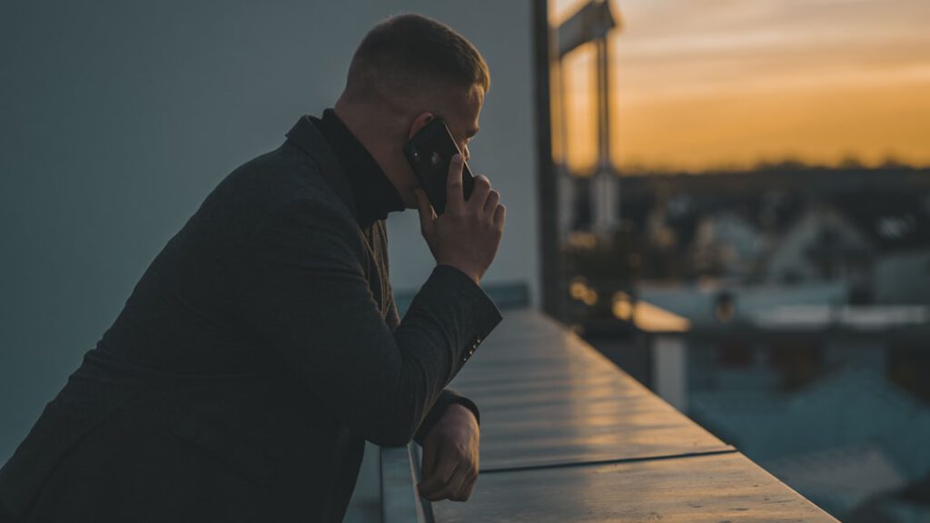 Hombre al teléfono en una terraza al atardecer, caso de amenazas o coacciones asesorado por Bufete Paredes & Asociados