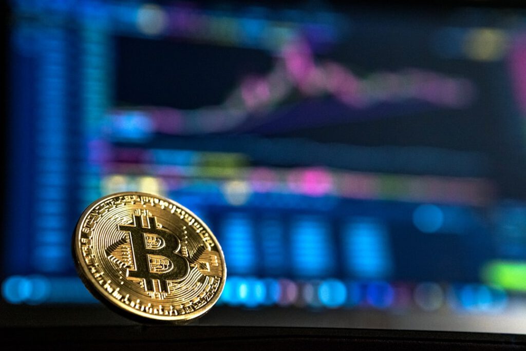 Moneda de Bitcoin ante gráficas de inversión, símbolo de estafas en plataformas cripto que Bufete Paredes & Asociados ayuda a recuperar