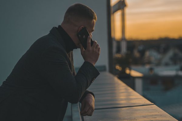 Hombre al teléfono en una terraza al atardecer, caso de amenazas o coacciones asesorado por Bufete Paredes & Asociados
