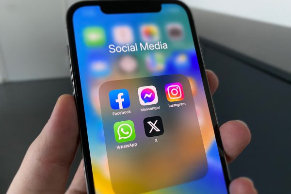 Mano sosteniendo un iPhone con apps de redes sociales, donde injurias online pueden ser delito según Bufete Paredes & Asociados